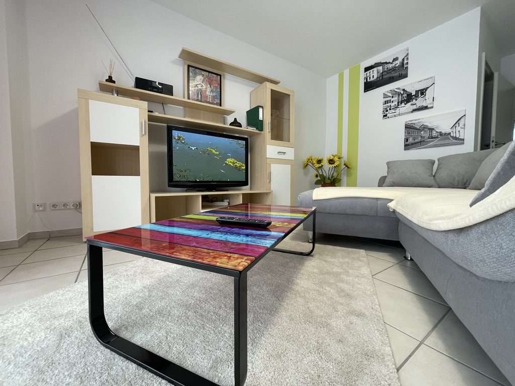 Startseite Heller Wohnbereich mit Fernseher und farbigem Couchtisch