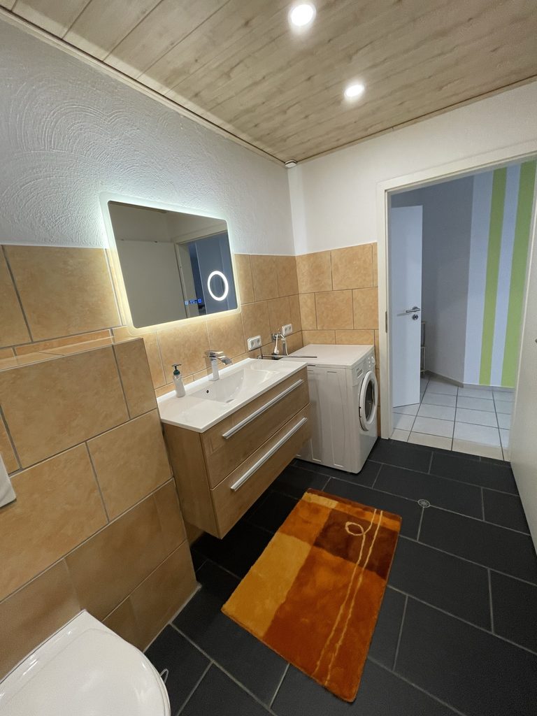 Startseite Badezimmer mit Waschtisch, Spiegel und Waschmaschine